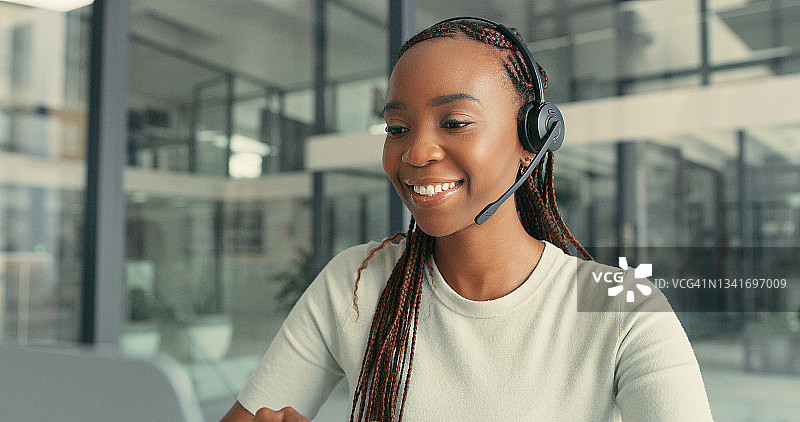 年轻女人在办公室用耳机和电脑图片素材
