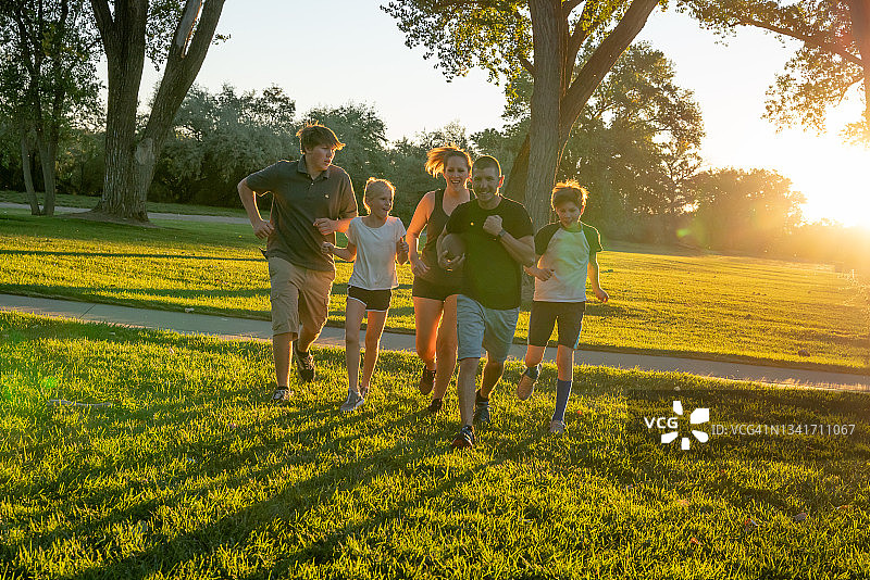 傍晚公园里享受橄榄球乐趣的五口之家图片素材