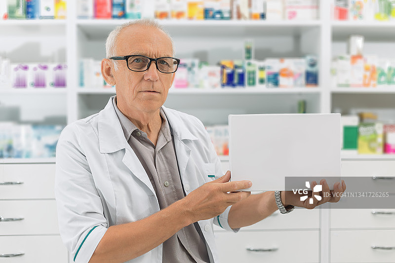 男药剂师拿着一个白色药盒图片素材