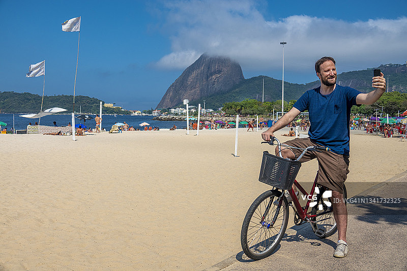 男人在面包山和弗拉门戈海滩背景下自拍图片素材
