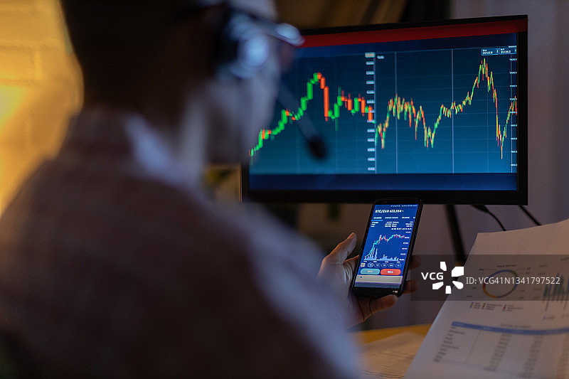 男人在家用手机查看货币交易应用程序图片素材