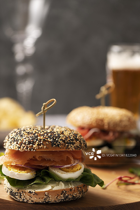 巨大的百吉饼，配有鲑鱼、鸡蛋和蔬菜，还有一杯啤酒图片素材