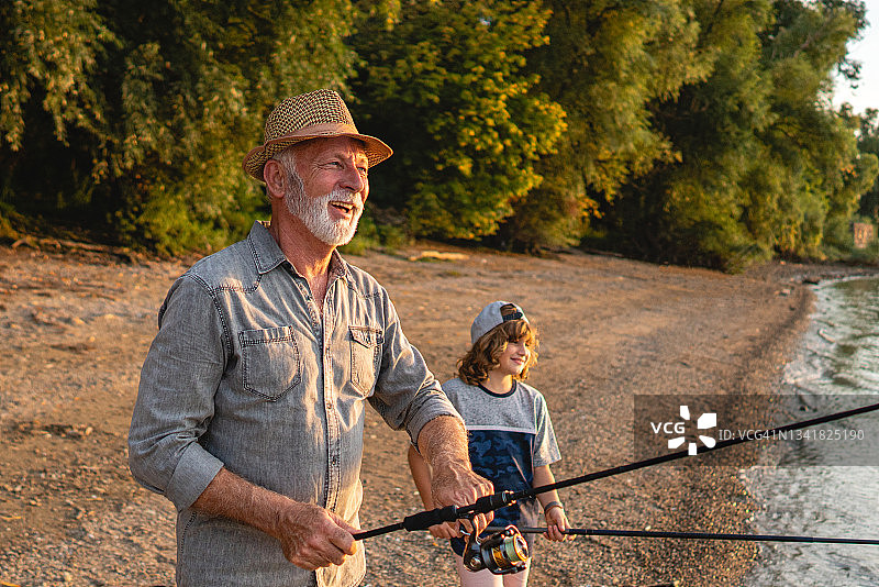 爷爷和孙子在河边钓鱼，享受美好时光图片素材