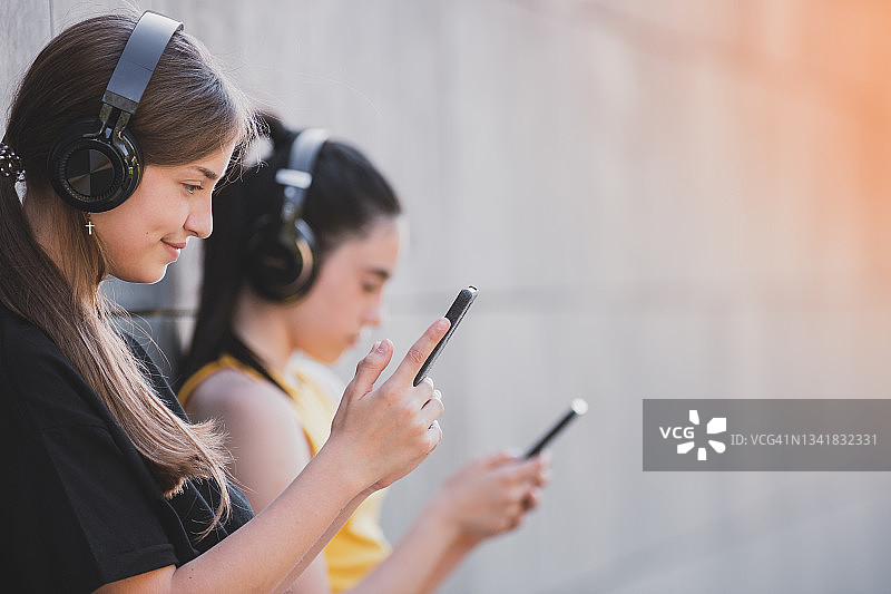 用蓝牙耳机和智能手机听音乐的快乐青少年图片素材