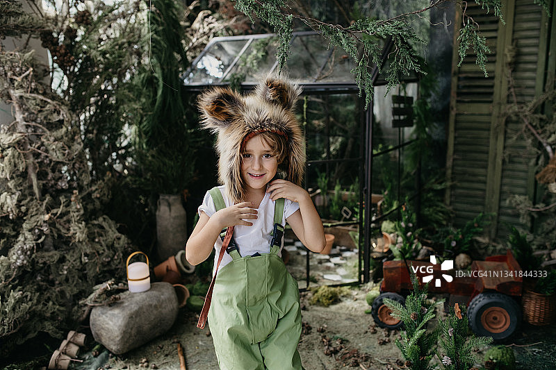 戴着狐狸帽在花园里看镜头的男孩图片素材