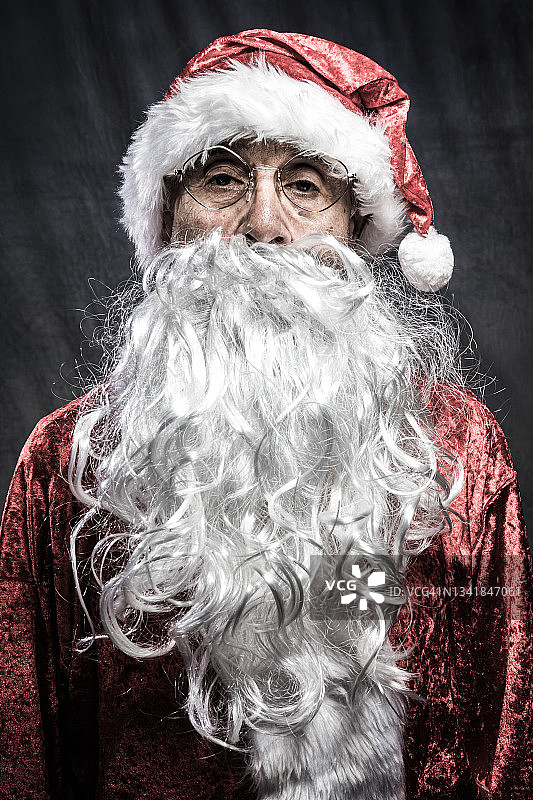 复古灰色背景下摆姿势的圣诞老人，面色严肃图片素材