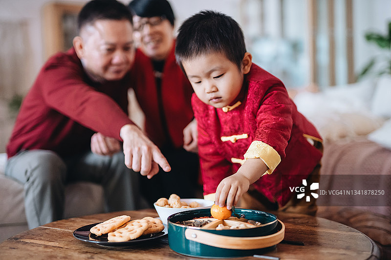 可爱的小孙子帮助祖父母准备新年糖果盒，庆祝中国新年图片素材