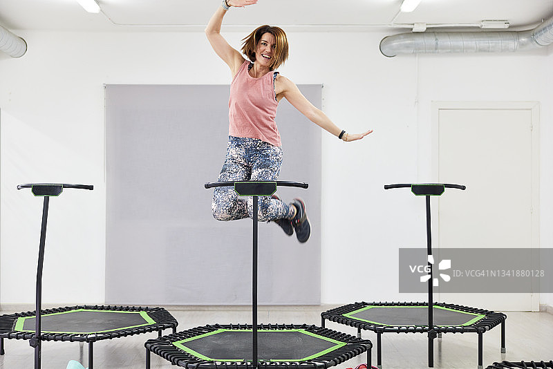 一位女士在健身蹦床上跳跃并做手势图片素材