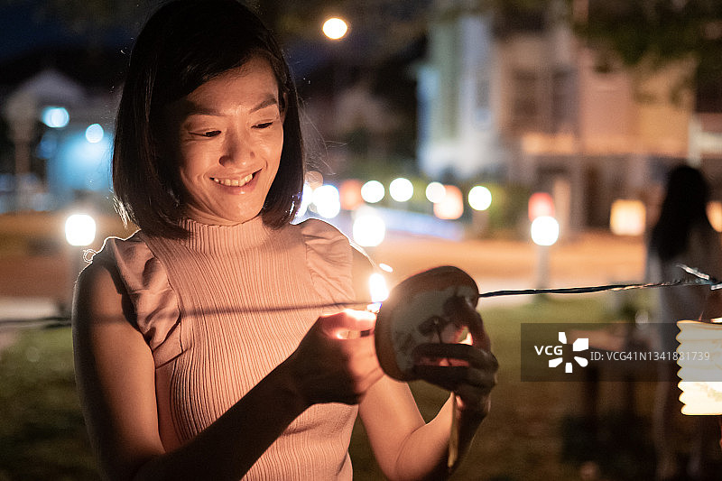 中国妇女在纸灯笼里点燃蜡烛，庆祝中秋节图片素材