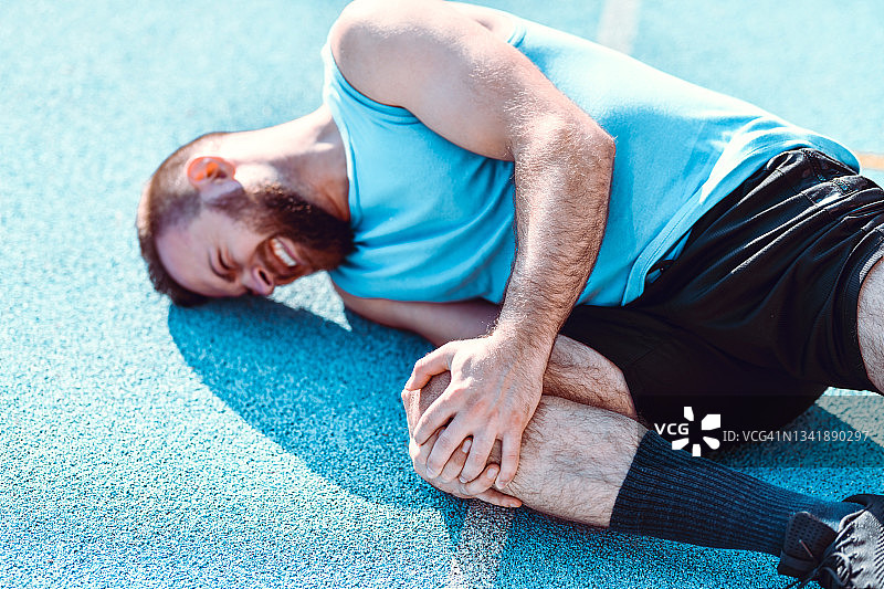 男运动员在训练中膝盖受伤后痛苦地躺在地上图片素材