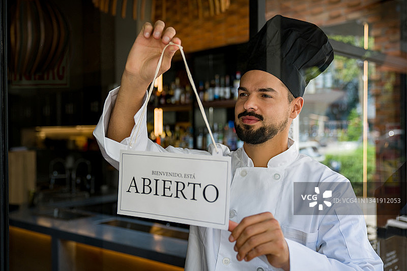 快乐的厨师在餐厅挂开放标志图片素材