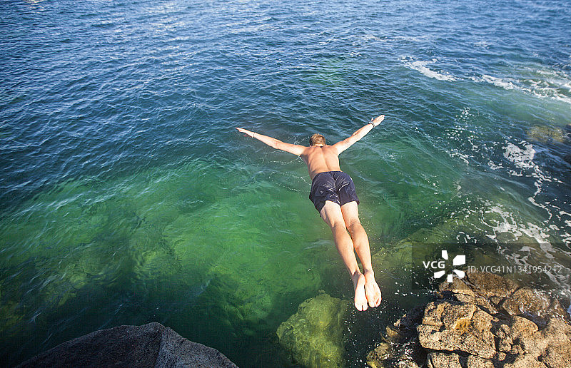 没穿衬衫的男人在海水中跳跃图片素材