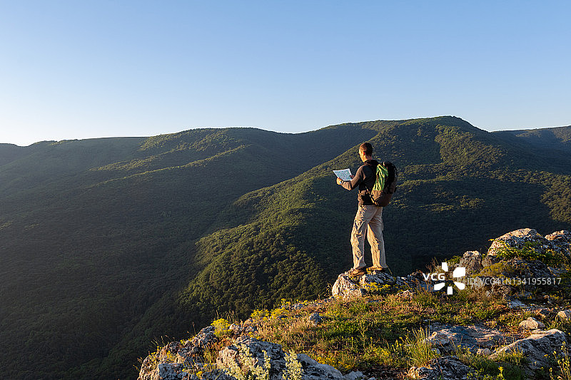旅行者在日出时站在山脊边缘阅读地图图片素材