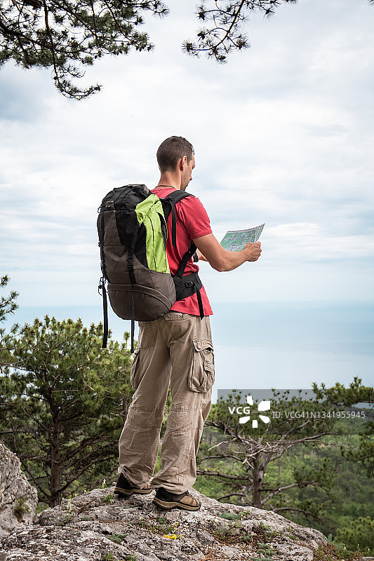 站在悬崖边查看地图的背包旅行者图片素材