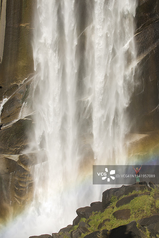 年轻女子在巨型瀑布下庆祝图片素材