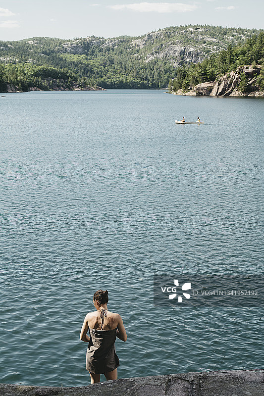 裹着毛巾，湖上划着独木舟的年轻女人图片素材