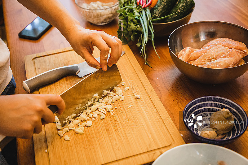 在厨房切蒜的亚洲女人（用新鲜食材准备健康食品）图片素材