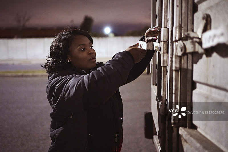 固定送货车车门的年轻女卡车司机图片素材