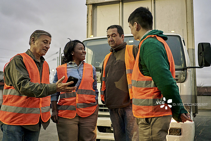 卡车司机朋友们在智能手机上交谈和分享照片图片素材