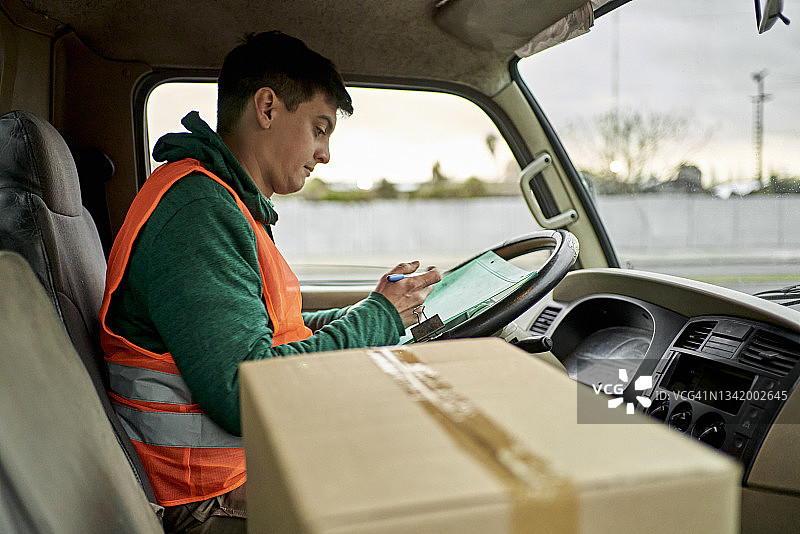 30岁出头的男人卡车司机在驾驶室检查文件图片素材