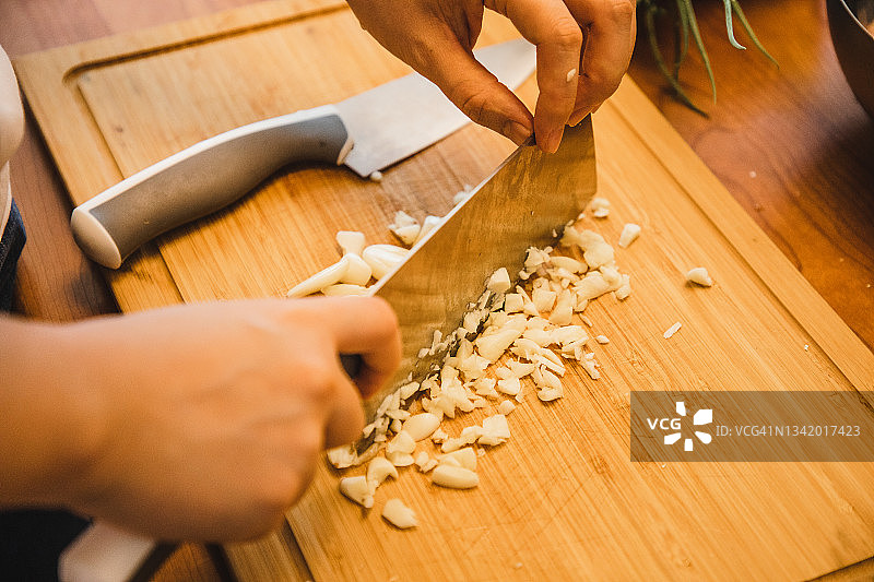 在厨房切蒜的亚洲女人（用新鲜食材准备健康食品）图片素材