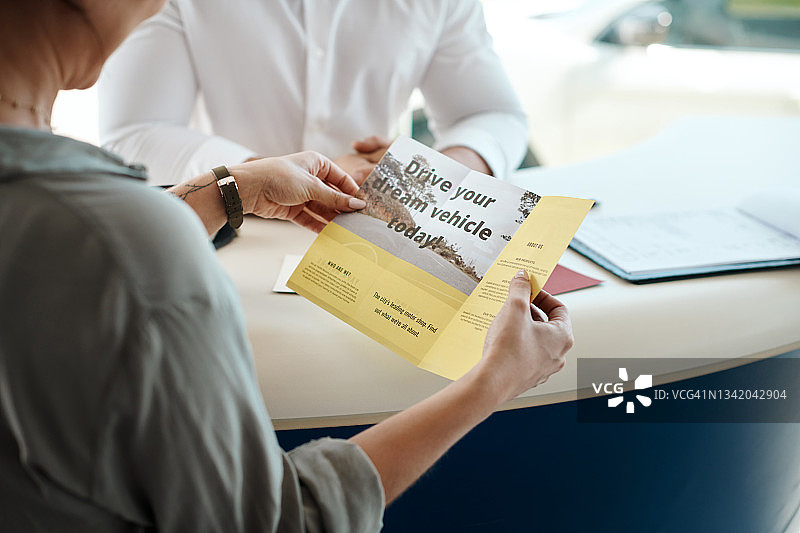 女子在决定购买哪辆车时阅读宣传册的照片图片素材