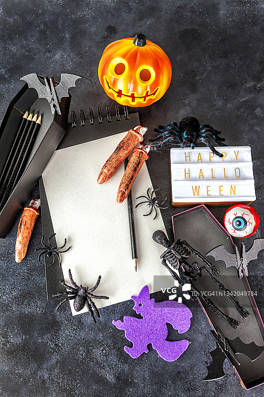 俯视视角：黑色背景上的万圣节装饰与空白螺旋笔记本样机图片素材