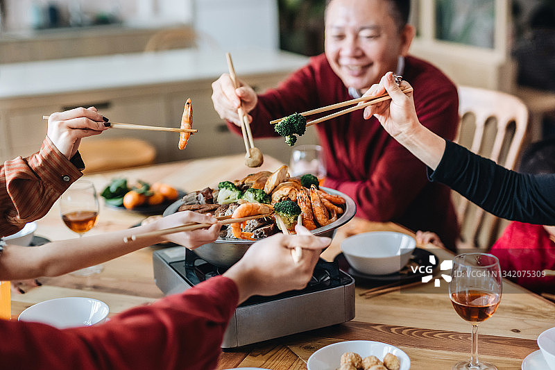 特写：喜悦的亚洲家庭三代人庆祝中国新年，享用美味的传统中国盆菜团圆饭图片素材