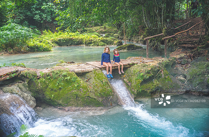 孩子们在郁郁葱葱的热带泻湖瀑布旁度假图片素材