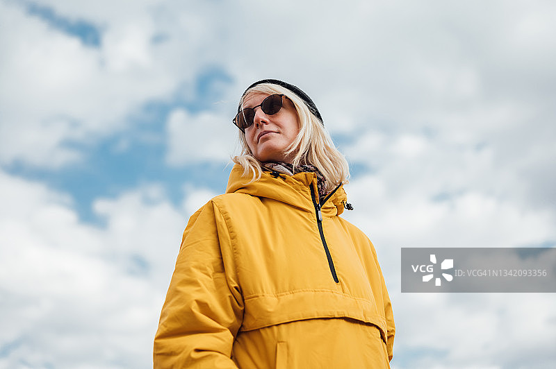 身穿黄色夹克的城市年轻女子，背景为蓝天图片素材