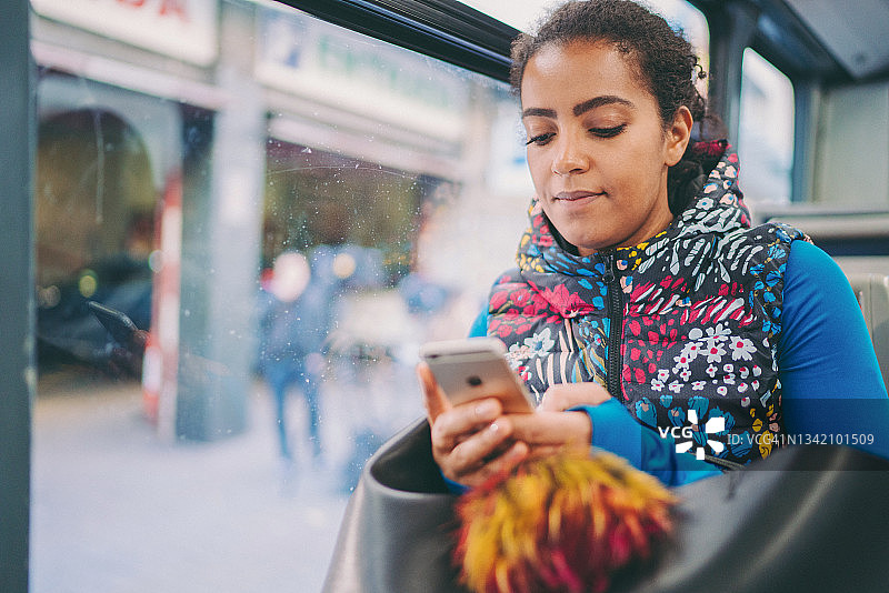 公交车上的混血女人用智能手机打字图片素材