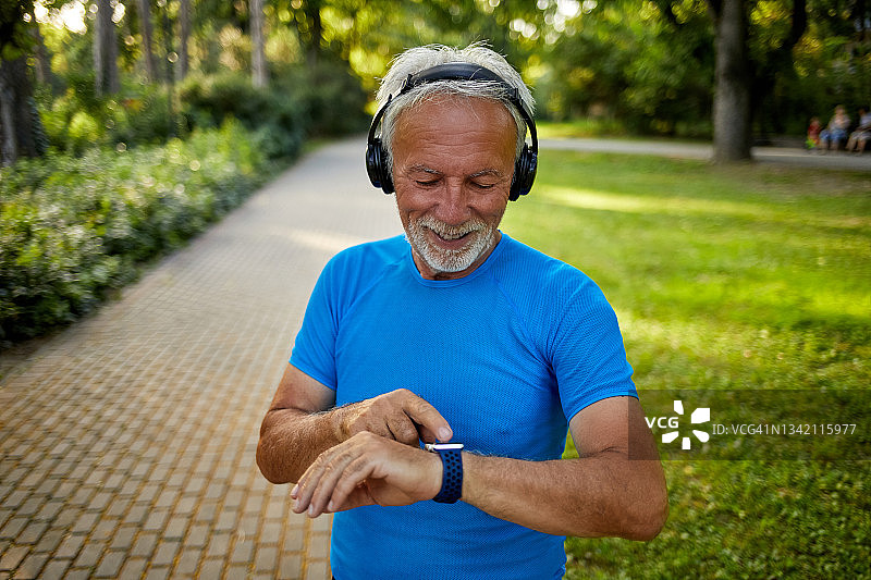 在户外锻炼时使用智能手表的年长男人图片素材