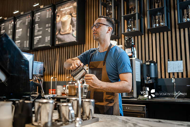 男咖啡师在吧台为顾客制作咖啡图片素材