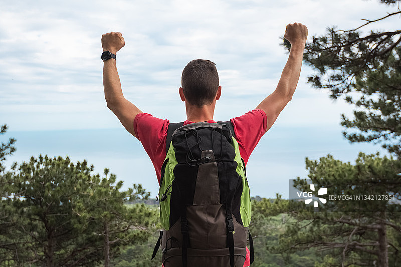 成功的旅行者在山地森林中到达目标并举手欢呼图片素材