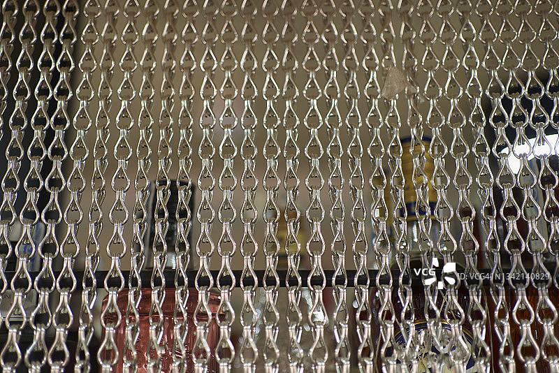 链条帘幕覆盖白色墙壁背景上架子上的一些玻璃瓶特写图片素材