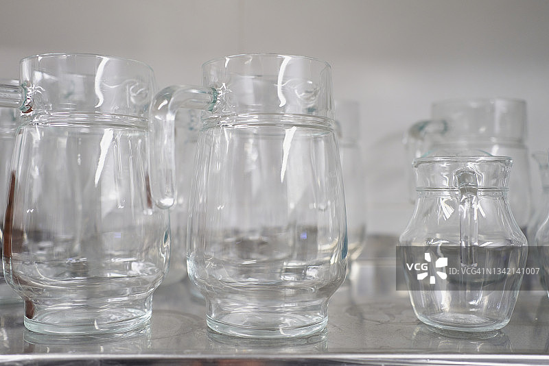 白色背景下金属柜台上空水晶玻璃罐特写图片素材