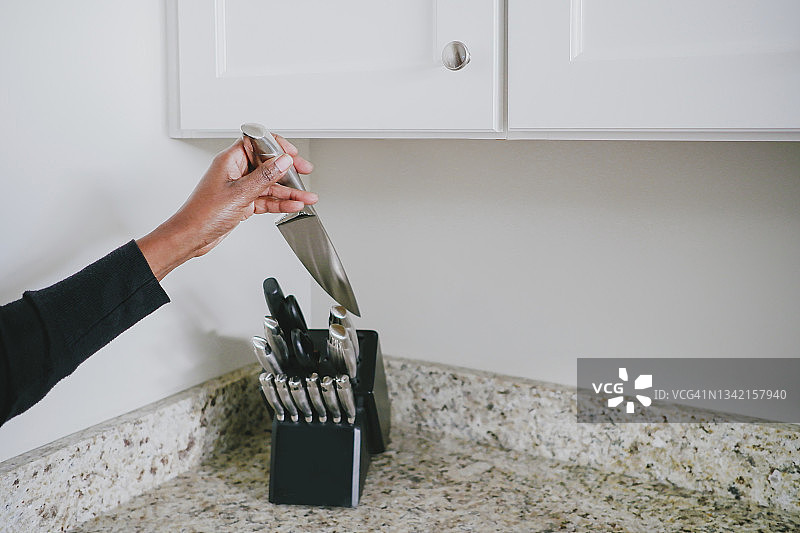 女人从刀架上拿起刀图片素材