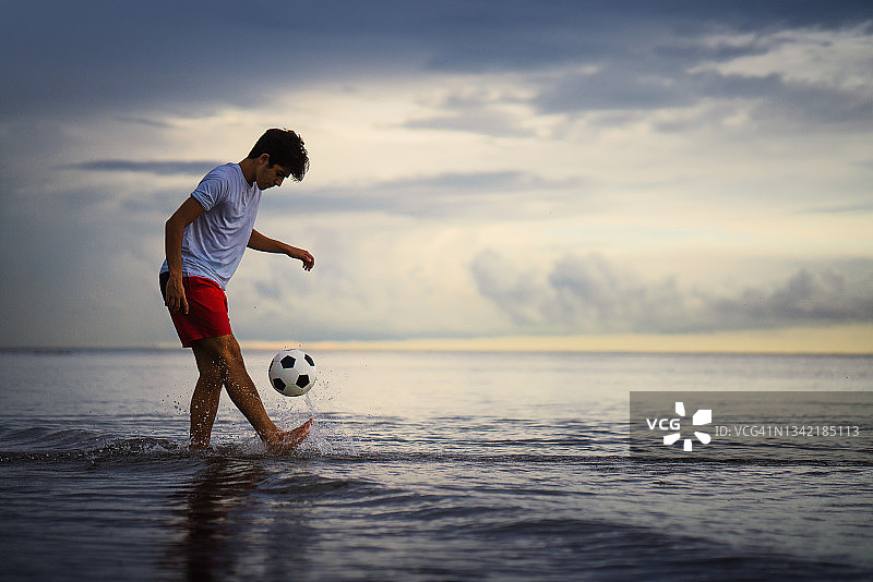 青少年在迈阿密海滩上玩足球图片素材