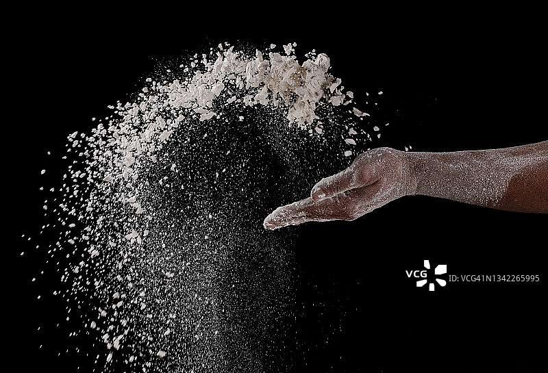 黑色背景下手撒面粉特写图片素材
