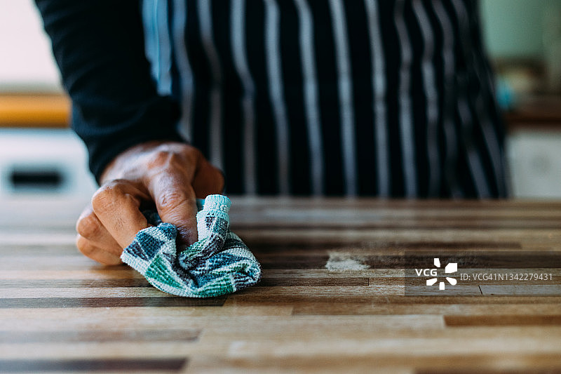 男子在家用清洁布清洁桌子表面的手部特写图片素材