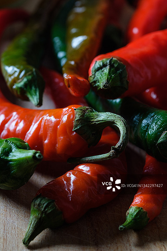 木制背景或厨房桌子上成熟和未成熟的红绿辣椒，有机农产品种植，美食烹饪香料图片素材