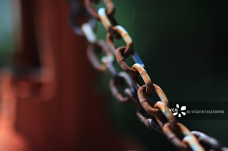 深色背景前对角线构图的锈链图片素材