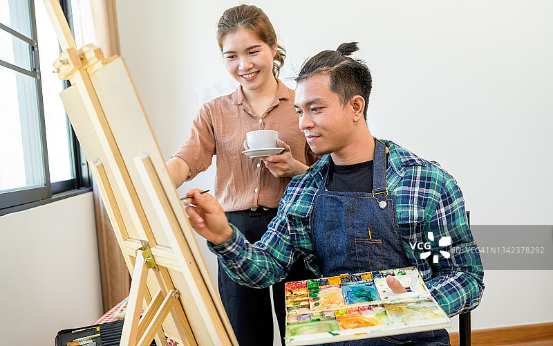 年轻男艺术家在画室里和女友一起创作图片素材