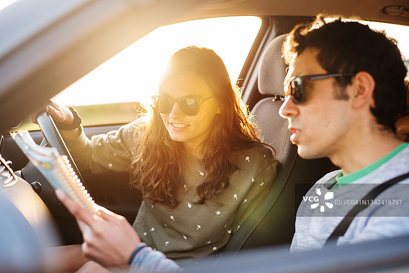 笑容满面的年轻朋友在公路旅行时看地图图片素材