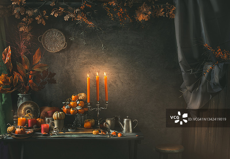秋季氛围静物：摆放南瓜、橙色蜡烛、茶杯和复古茶壶的桌子图片素材