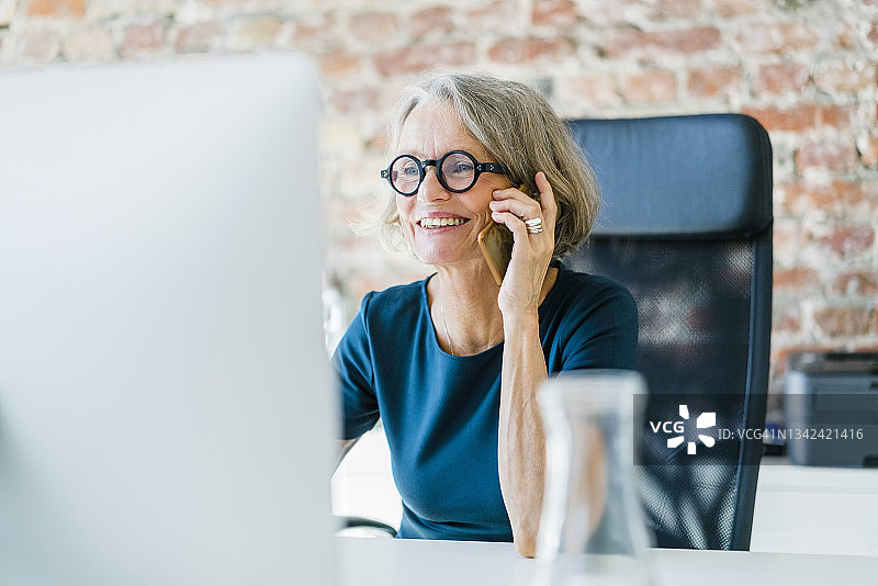 女商人在她的办公桌上用手机图片素材