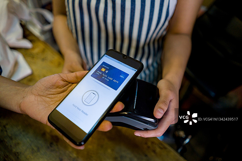 顾客在杂货店进行非接触式支付的特写图片素材