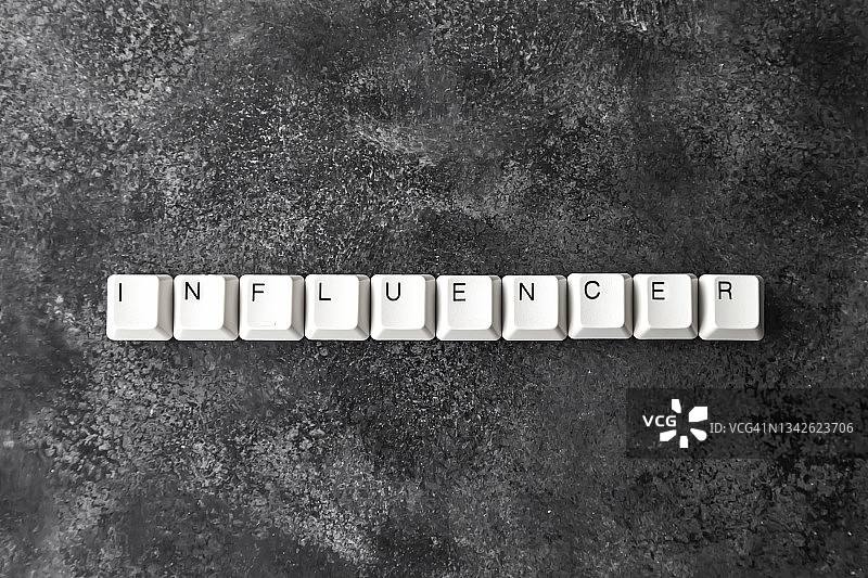 拼写“INFLUENCER”一词的电脑键盘按键，黑色背景图片素材