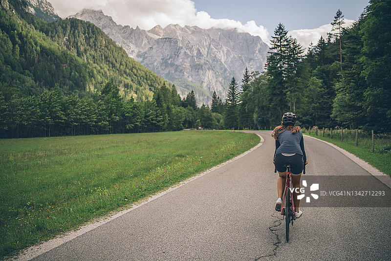 女人在阳光明媚的乡村道路上骑公路自行车图片素材