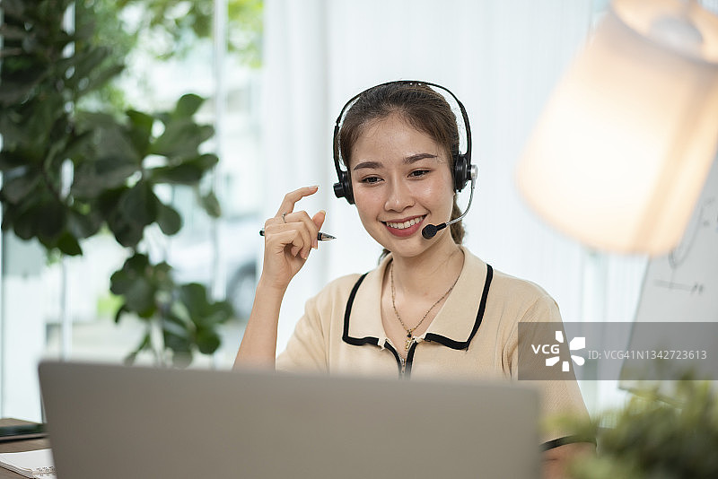 戴着耳机在笔记本电脑上写笔记学习的快乐女孩翻译员图片素材